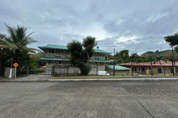 Edificio de tres pisos con 8 unidades y una casa pequeña.